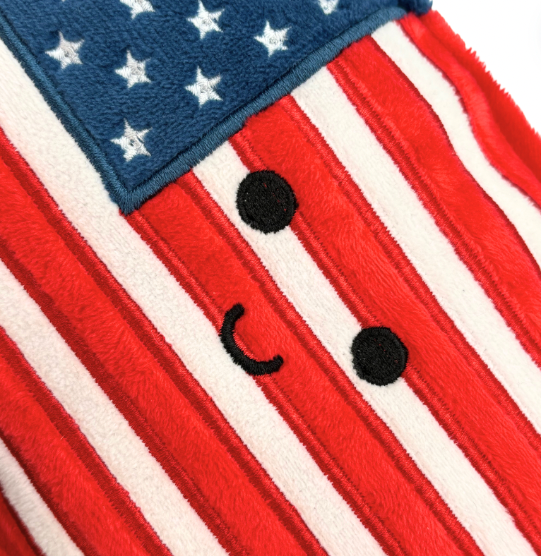 Stuffed American Flag plush featuring 50 stars and 13 stripes, measuring 10 inches by 6 inches by 2 inches, perfect for collectors and gifts.