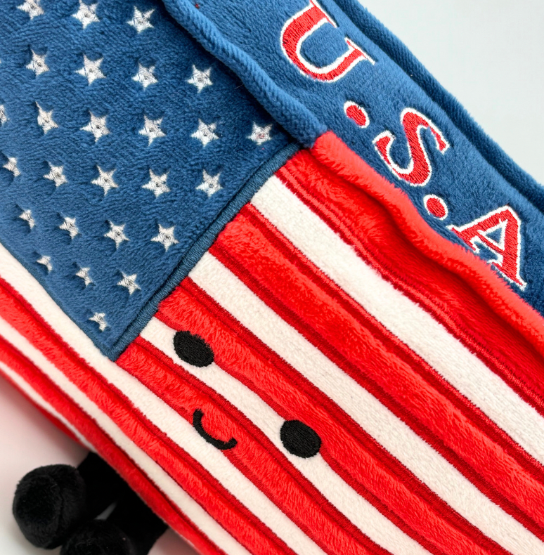 Stuffed American Flag plush featuring 50 stars and 13 stripes, measuring 10 inches by 6 inches by 2 inches, perfect for collectors and gifts.